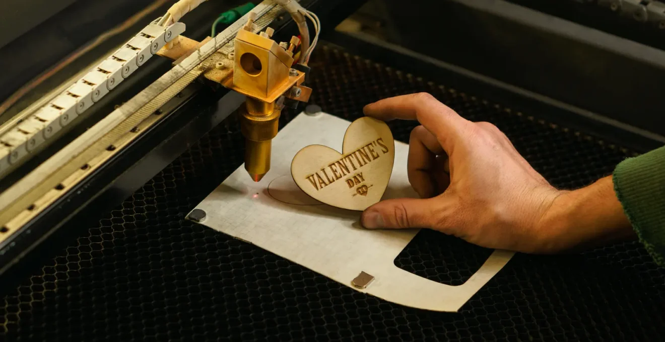 Un technicien grave un logo au laser sur une clé USB métallique en atelier.